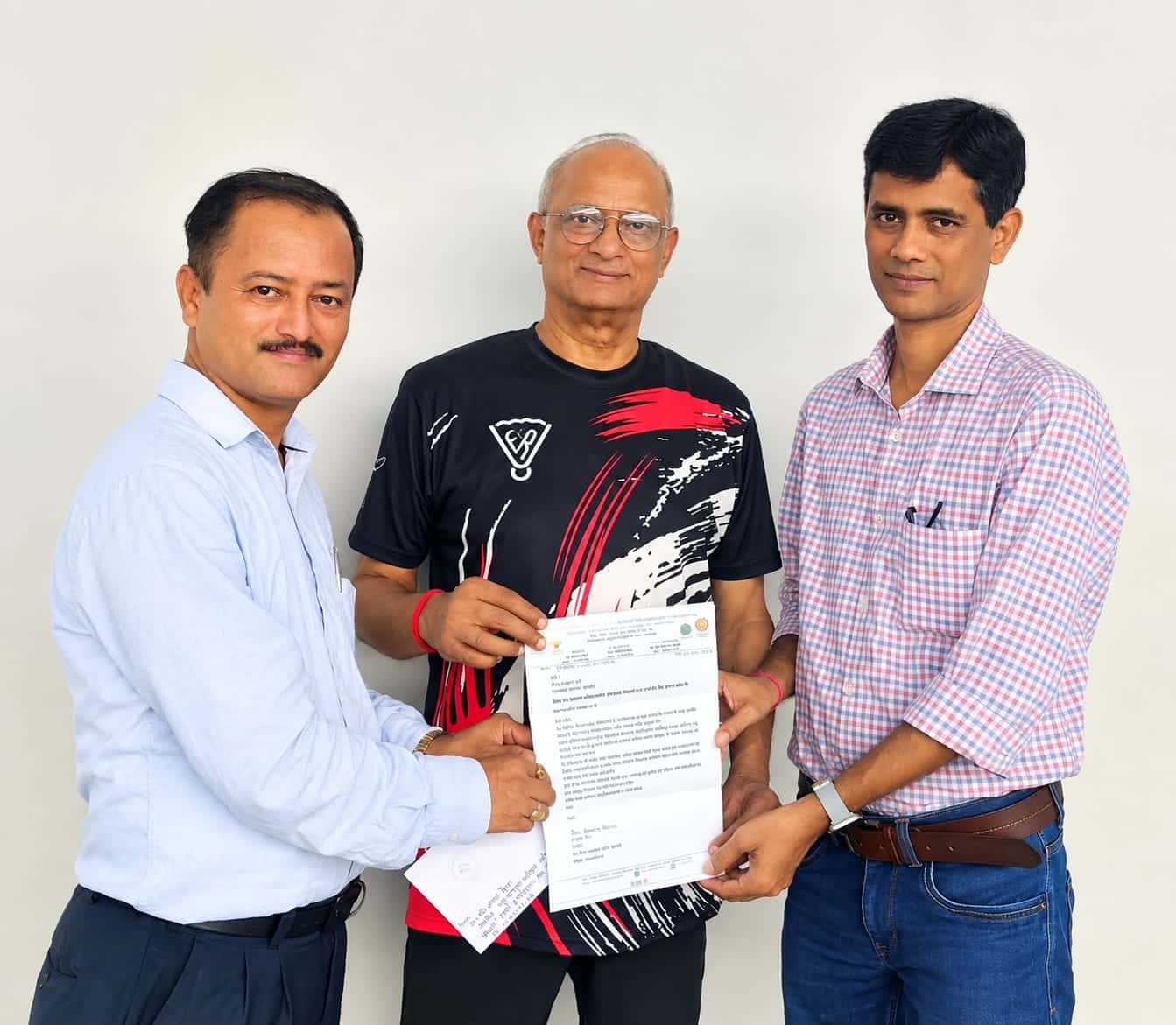 यह फोटो उस खबर के लिए मुख्य/Featured Photo के रूप में इस्तेमाल की जा सकती है। तस्वीर में तीन लोग एक दस्तावेज/पत्र को कैमरे के सामने दिखाते हुए नजर आ रहे हैं।
