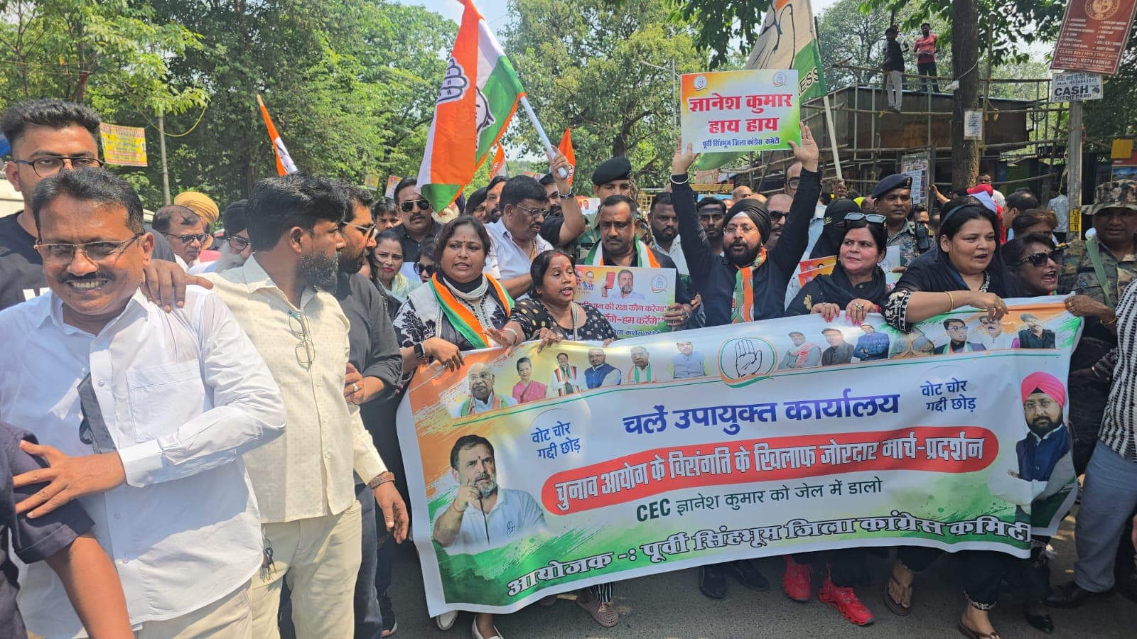 कांग्रेस कार्यकर्ता और नेता एक बड़े बैनर के साथ सड़क पर मार्च करते दिखाई दे रहे हैं। बैनर पर चुनाव आयोग की कार्यप्रणाली के विरोध और उपायुक्त कार्यालय तक मार्च का उल्लेख है। तस्वीर में कांग्रेस के झंडे और प्रदर्शन में शामिल लोगों की भीड़ दिखाई दे रही है।