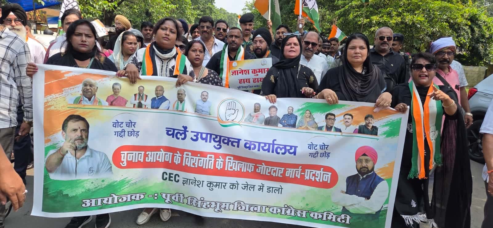 जमशेदपुर में कांग्रेस कार्यकर्ता एक बड़े बैनर के साथ मार्च और प्रदर्शन करते हुए दिखाई दे रहे हैं। बैनर पर चुनाव आयोग की कार्यप्रणाली के विरोध में उपायुक्त कार्यालय तक मार्च का उल्लेख है। तस्वीर में कांग्रेस के झंडे और बड़ी संख्या में कार्यकर्ता नजर आ रहे हैं।