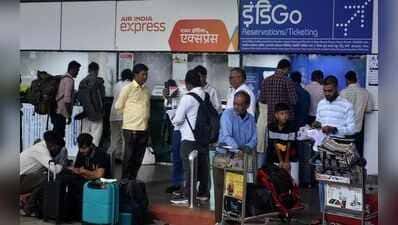एयर इंडिया एक्सप्रेस और इंडिगो के बोर्ड वाले परिसर में सामान की ट्रॉलियों और बैग के साथ कई लोग खड़े दिखाई दे रहे हैं। कुछ यात्री फर्श पर बैठे हैं।